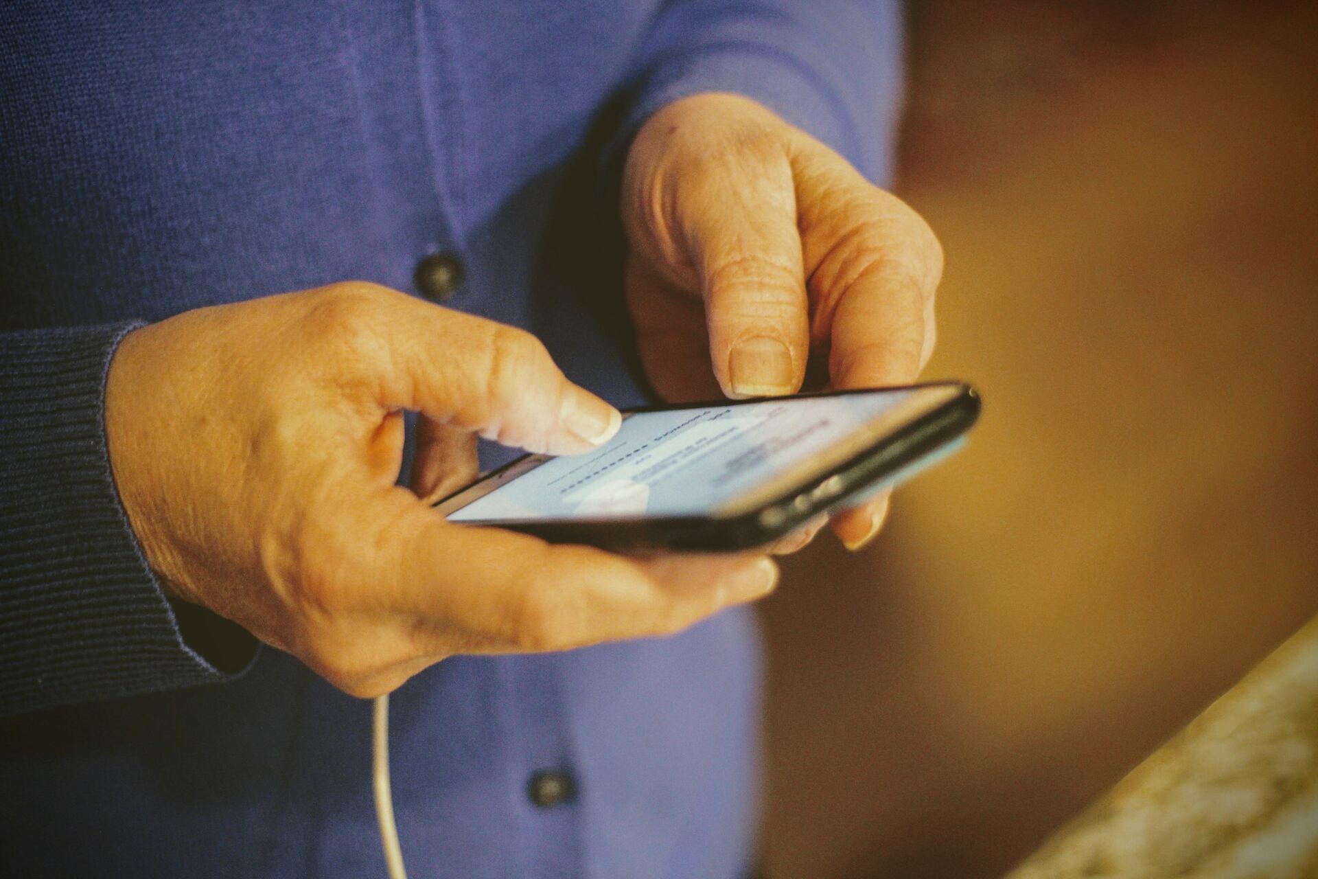 Mains d’une personne âgée tenant un téléphone